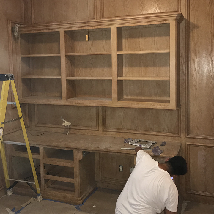 Unfinished wooden cabinets and desk area, setup with tools, awaiting painting.