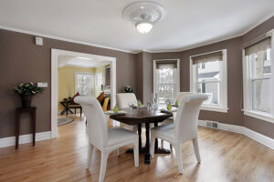 A beautiful dining room with brown walls, double-hung windows, and a square dining room table