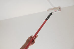 A paint roller extended to paint the ceiling