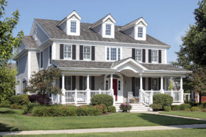 Picture of the exterior of a house with a large front porch and recently painted siding.